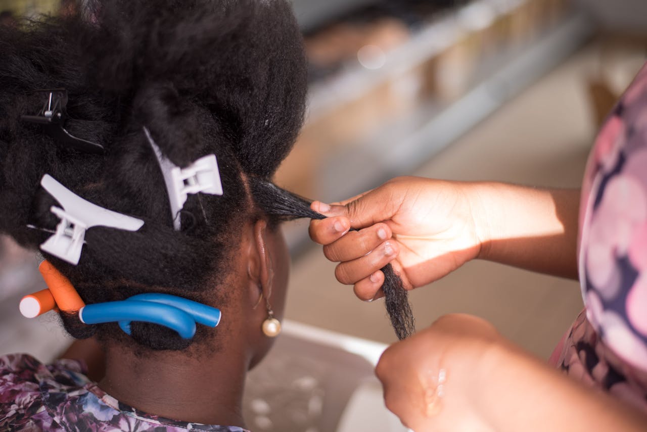 Hairdresser styling a woman's hair with clips in a salon. Close-up of hands and hair.