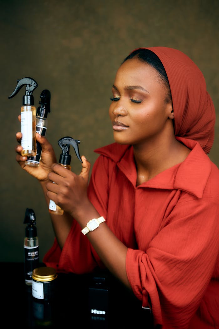 A woman in red showcasing hair care spray bottles with a serene expression.