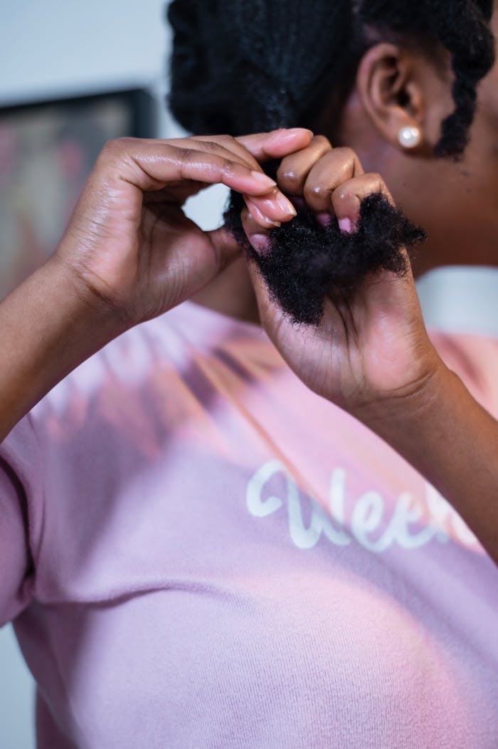 Detailed view of a woman styling her curly hair indoors, focusing on personal care.